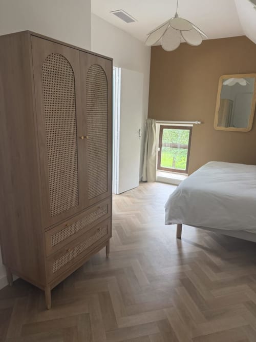 Chambre moderne au Clos de l'Arguenon avec armoire en bois, lit et vue sur le jardin de Val-d'Arguenon