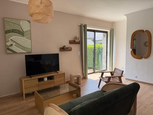 Séjour moderne au Gîte Le Clos de l'Arguenon à Val-d'Arguenon avec mobilier en bois, grand écran TV et accès au jardin