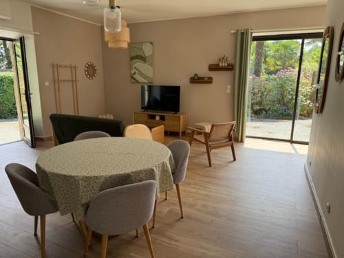 Spacieux séjour ouvert au Clos de l'Arguenon avec table ronde, mobilier moderne et vue sur le jardin