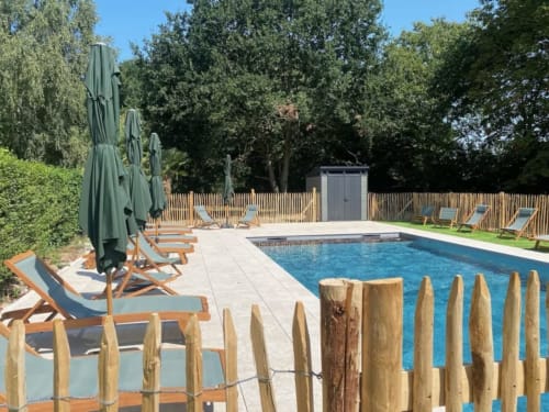 Espace piscine du Clos de l'Arguenon avec transats, parasols et clôture en bois à Val-d'Arguenon