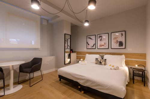 Camera moderna a CASA LOUNGE ISTRIA a Cagliari con letto queen, testata in legno, luci a sospensione e vista sulla città