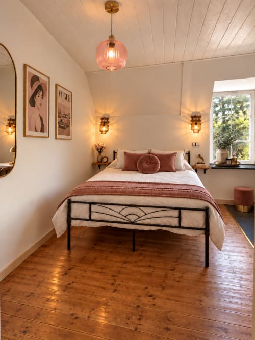 Chambre rétro-chic à la L'Echappée Baie avec lit en métal, touches de terre cuite chaleureuse et vue sur le jardin à Roz-sur-Couesnon