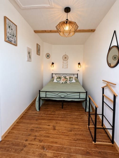 Chambre rétro-chic à L'Échappée Baie B&B à Roz-sur-Couesnon avec lit en métal, poutres apparentes et éclairage chaleureux