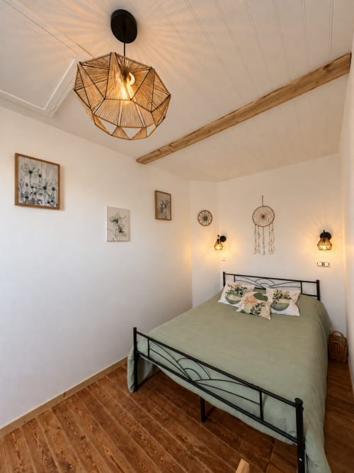 Chambre rétro-chic douillette à L'Echappée Baie : linge de lit sauge, luminaires suspendus et art botanique mural