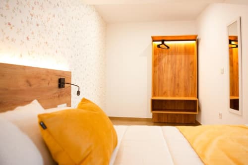 Acogedora habitación del Hostal Restaurante Angel en Huelma con cabecero de madera, toques amarillos y armario.