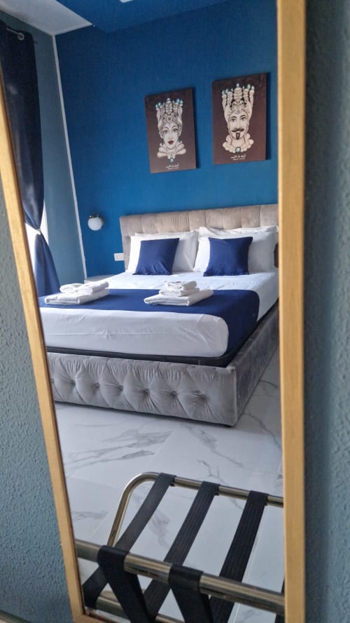 Camera moderna dell'U Baruni B&B a Messina con pareti blu, opere d'arte decorativa e biancheria bianca con accenti blu navy