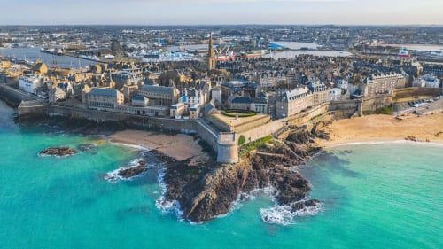 Vue aérienne d'une ville côtière fortifiée aux eaux turquoise, falaises dorées et plages près de Roz-sur-Couesnon, Bretagne