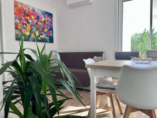Elegante zona living di Villa Eraklea a Noto con opere d'arte floreale colorata, piante in vaso e arredamento contemporaneo
