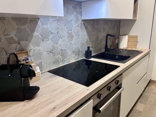 Cucina moderna di Villa Eraklea B&B Noto con piano cottura nero, armadiature bianche e rivestimento geometrico