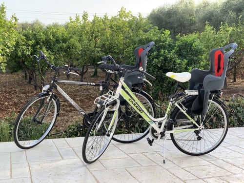 Biciclette con seggiolini per bambini a Villa Eraklea a Noto, Italia, con vigna sullo sfondo