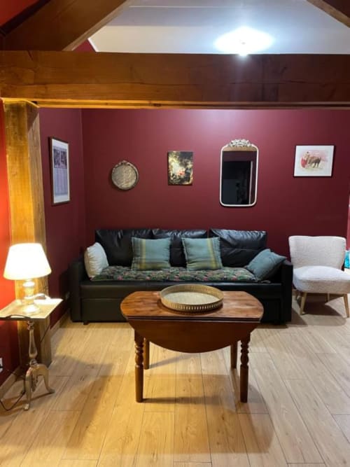 Salon bourguignon au Clos d'Émilie avec canapé noir, table en bois et éclairage ambiant
