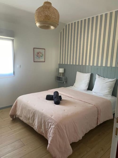 Chambre Carmen du gîte Le Clos d'Émilie avec papier peint rayé, suspension tissée et couvre-lit rose