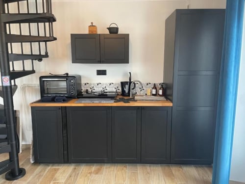 Kitchenette moderne à la maison de Suzanne, Le Clos d'Émilie, avec meubles noirs et plan de travail en bois
