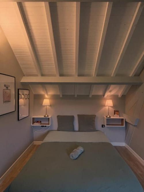 Chambre douillette sous les toits au Clos d'Émilie avec poutres apparentes, lampes jumelles et parquet