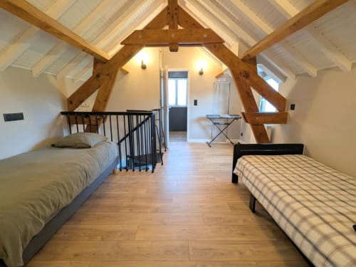 Chambre mansardée lumineuse au Clos d'Émilie avec poutres apparentes, deux lits, parquet et fenêtres de toit