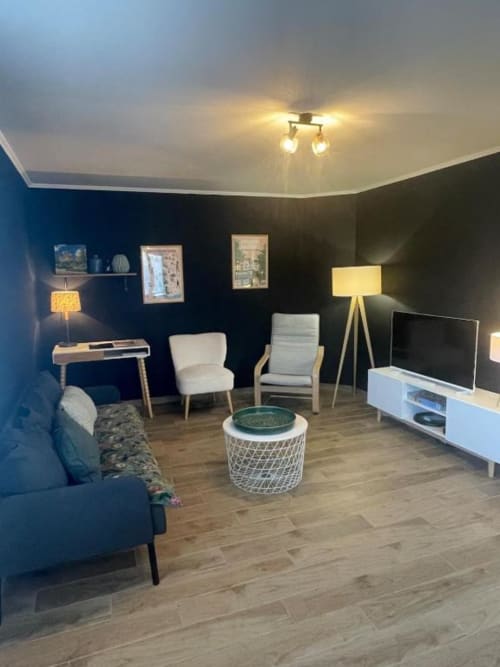 La chambre de Suzanne au Clos d'Émilie : murs bleu foncé, mobilier contemporain, meuble TV blanc et ambiance chaleureuse