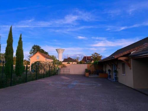 Cour du Clos d'Émilie au crépuscule : dallage en pierre, cyprès et bâtiments français traditionnels sous ciel bleu
