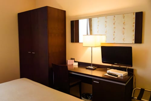 Camera moderna dell'Hotel FortyFive con scrivania scura, TV a schermo piatto, lampada da tavolo e armadio a Chivasso