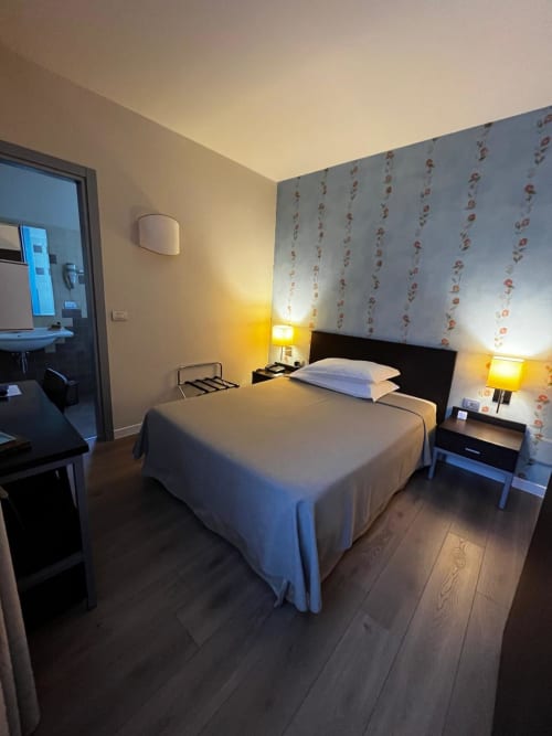 Camera accogliente all'Hotel FortyFive a Chivasso con letto queen, carta da parati floreale, illuminazione calda e pavimenti in legno scuro