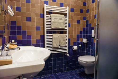 Bagno dell'Hotel FortyFive a Chivasso con piastrelle blu e beige, lavandino bianco, water e scaldasalviette riscaldato beige
