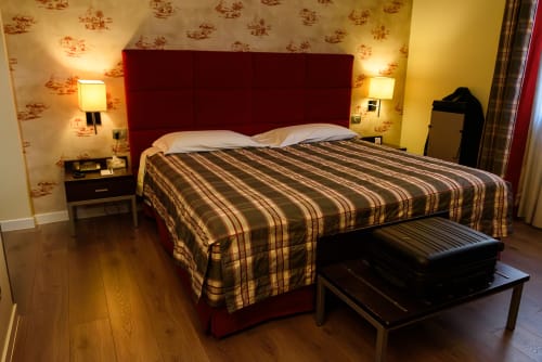 Camera superiore presso l'Hotel FortyFive a Chivasso con testata rossa, biancheria a righe e illuminazione calda