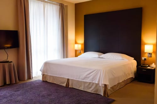 Camera deluxe all'Hotel FortyFive a Chivasso con letto king, testata nera, pareti dorate, lampade moderne e