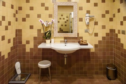 Elegante bagno nella camera Deluxe dell'Hotel FortyFive, Chivasso, con piastrelle a scacchi, lavabo bianco e specchio decorativo