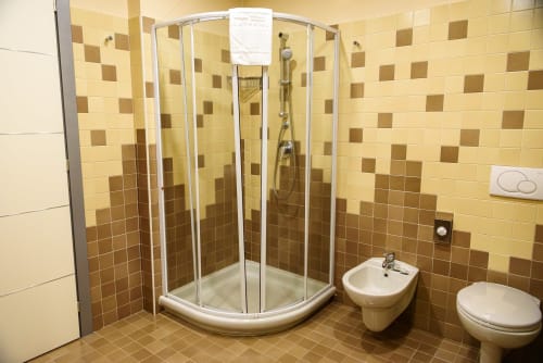 Bagno moderno della camera Deluxe Hotel FortyFive con doccia angolare, bidet, wc e pareti piastrellate color crema