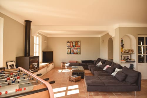 Salle de séminaire spacieuse aux Hauts De Diane à Cuers avec baby-foot, cheminée, canapé foncé et vue sur le jardin