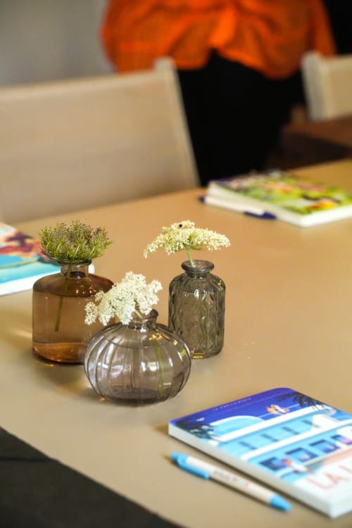 Vases en verre avec fleurs blanches délicates sur table de salle de séminaire en bois aux Hauts De Diane, Cuers