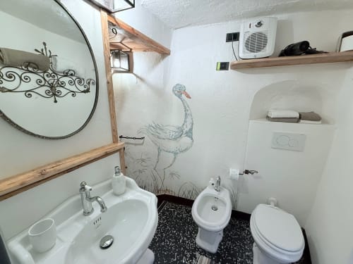 Il bagno privato della Suite Drago al Roseto del Drago a Ponte in Valtellina (Sondrio), caratterizzato da finiture curate, dettagli in legno, specchio decorato e dipinto murale artistico.