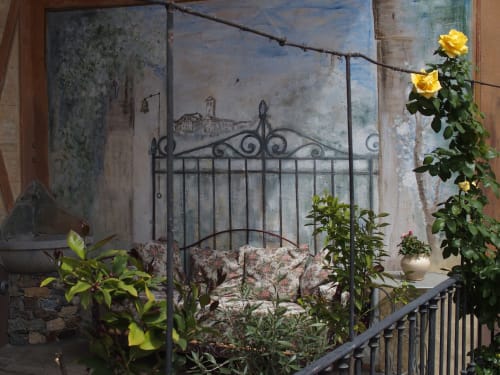 Area relax sul terrazzo coperto della Suite Drago al Roseto del Drago a Ponte in Valtellina (Sondrio), con elegante divanetto fiorito, fontanella in pietra e grande affresco a parete in trompe-l'œil.
