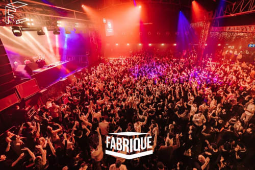 Fabrique nightclub at Unico Studios Milano features vibrant red and purple stage lighting with energetic crowd dancing