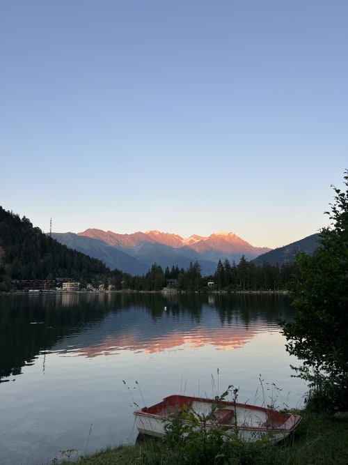 Bateau rouge et blanc sur le lac de Champex au lever du soleil avec montagnes enneigées, Hôtel Sunways à Champex-Lac