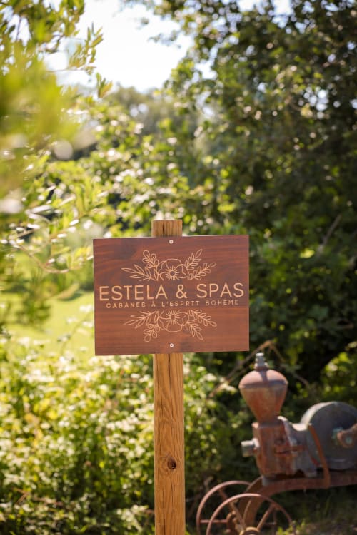 Enseigne en bois pour Estela & Spas dans un jardin luxuriant à Sant Feliu de Guixols
