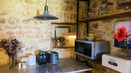 Rincón de cocina rústica en la villa Can Serrà 1786 de Llagostera con ladrillos vistos, lámpara colgante y electrodomésticos