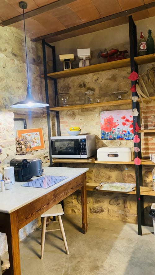 Espacio de cocina rústico de piedra en la villa Can Serrà 1786 en Llagostera con escritorio de madera, microondas y estanterías abiertas