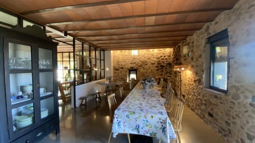 Comedor espacioso de la villa Can Serrà 1786 en Llagostera con mesa larga, vigas de madera y paredes de piedra