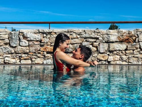 Couple profitant d'une magnifique piscine turquoise à l'hôtel Recantos D'Almerinda à Pombal, Portugal, avec murs en pierre