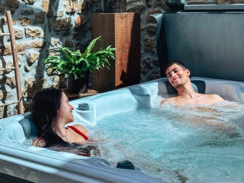 Casal desfrutando da banheira de hidromassagem no hotel Recantos D'Almerinda em Pombal com paredes de pedra e plantas