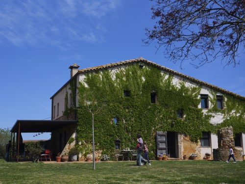 Villa histórica catalana Can Serrà de 1786 en Llagostera con fachada de piedra cubierta de hiedra y jardines bien cuidados