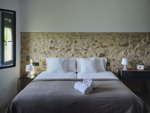 Dormitorio rústico de piedra con ropa de cama blanca y toallas enrolladas en la villa Can Serrà 1786 en Llagostera, España