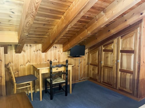 Chambre rustique avec charpente apparente, TV écran plat, bureau et moquette bleue à l'Hôtel les Bouquetins à Zinal