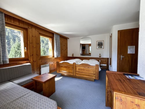 Chambre double spacieuse à l'Hôtel les Bouquetins à Zinal, mobilier en bois, vue montagne et coin détente