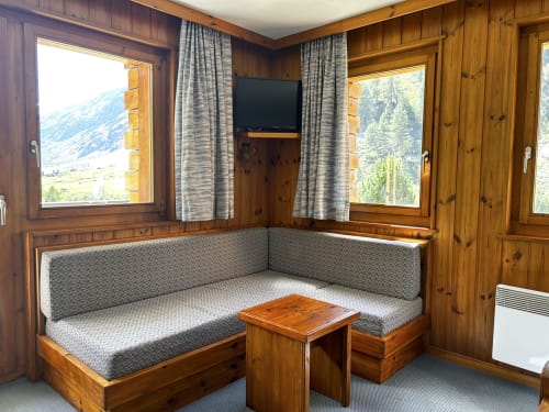 Chambre alpine douillette à l'Hôtel les Bouquetins, Zinal, avec boiseries, vue montagne, coins assises intégrés et TV écran plat