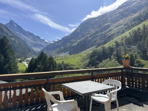 Terrasse panoramique de l'Hôtel les Bouquetins à Zinal offrant vue sur la vallée alpine, pics enneigés et mobilier extérieur