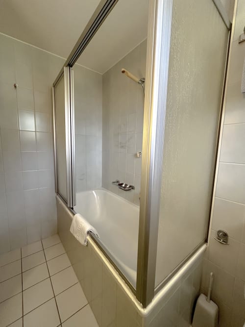 Salle de bain moderne avec baignoire et cabine de douche vitrée à l'Hôtel les Bouquetins à Zinal, Suisse