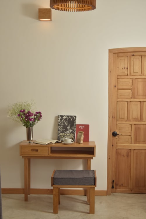 Escritorio de madera con flores moradas y libros en la habitación del hotel Casa Cafeólogo, San Cristóbal de las Casas