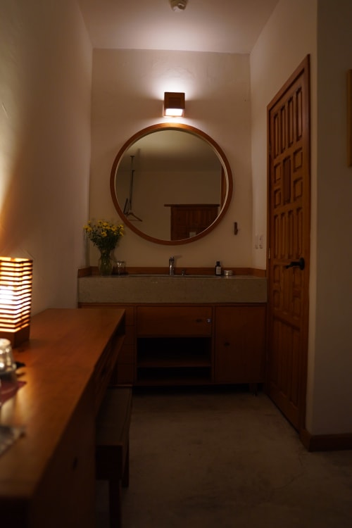 Baño moderno con espejo circular y lavamanos de piedra en el hotel Casa Cafeólogo, San Cristóbal de las Casas, México