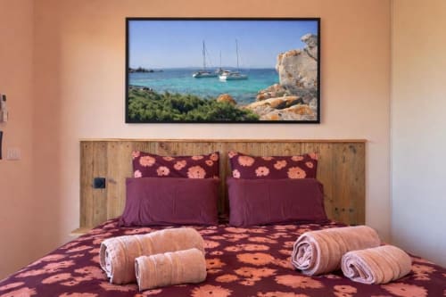 Chambre de villa à Porto-Vecchio avec art nautique encadré, literie fleurie bordeaux, tête de lit en bois et serviettes roulées